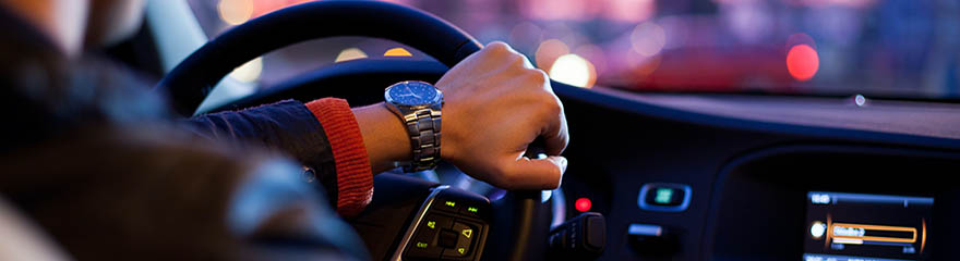 person wearing watch driving through city