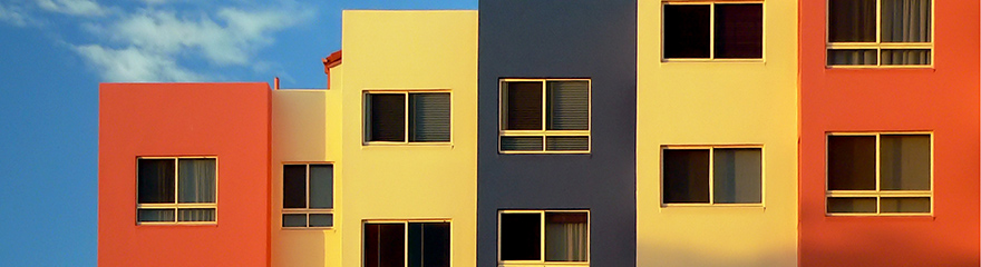 orange, yellow and grey apartment blocks against blue sky