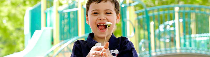 smiling boy holds flower at a playground