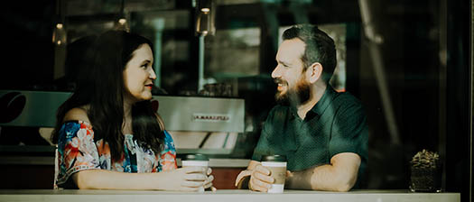two people out having coffee behind a street window