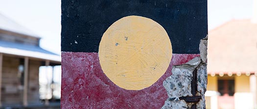 aboriginal flag painted in black, red and yellow on brick wall