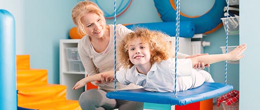 smiling boy on indoor swing with support person