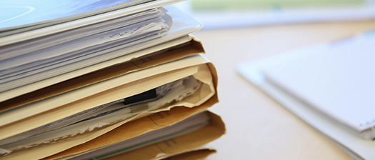 A stack of files in a manila folder on a desk.