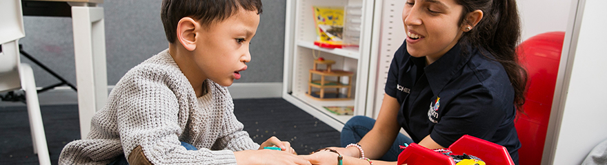 A child and support worker playing with toys on the floor