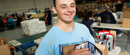 A smiling person looking towards screen in a warehouse environment
