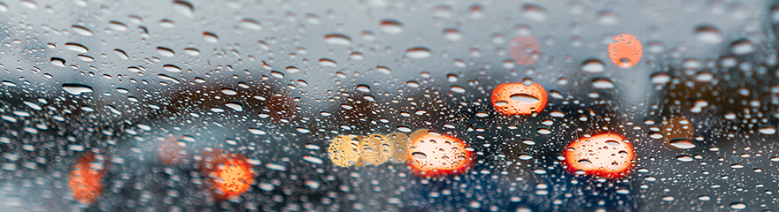 Out of focus image of rain on windscreen and car lights in distance