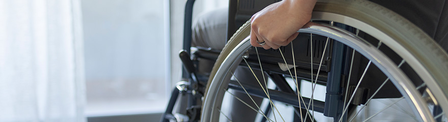 Close up of a hand resting on a wheel of a wheelchair