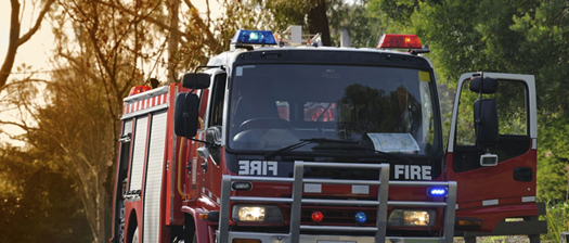 A fire truck drives along a bushland road