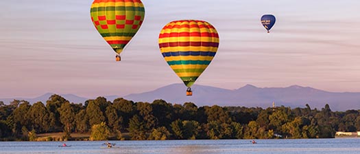 hot air balloons float over Lake Burley Griffin 