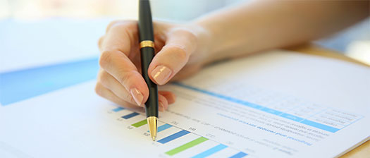 A woman's hand holds a pen over a piece of paper with a graph on it