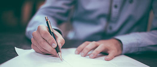 Close up of hands signing a blank page with a pen