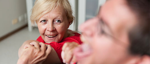 A support worker looks caringly towards the person they are supporting who is out of focus