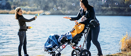 A mother having fun blowing bubbles with her two children, one is in a wheelchair