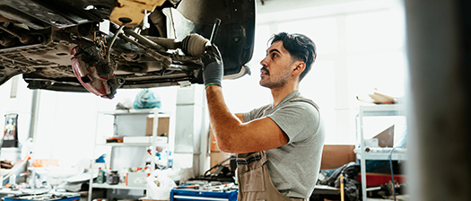 A mechanic works under a car on a hoist in an auto workshop