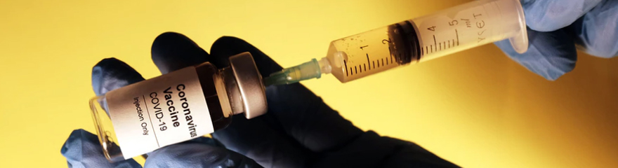 A close up of liquid being drawn from a vaccine vial with a syringe