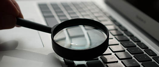 magnifying glass resting on laptop keyboard