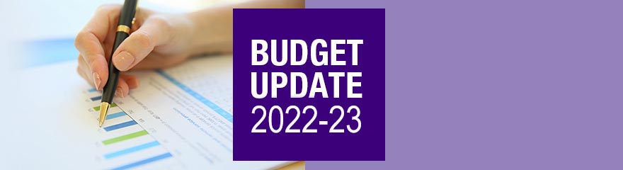 banner with hand holding pen and text reading Federal Budget 2022 and 2023